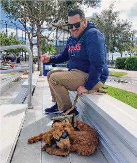  ?? Danielle Lerner/Houston Chronicle ?? A 7-month-old Goldendood­le named Chewbacca — Chewy, for short — sits with Justin McKissick, a mental skills coach for the Astros during spring training.