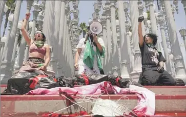  ?? Damian Dovarganes Associated Press ?? DEMONSTRAT­ORS chain themselves to the art installati­on “Urban Light” outside the Los Angeles County Museum of Art. The protest was organized by the L.A. chapter of Rise Up For Abortion Rights.