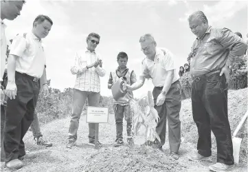  ??  ?? Law waters a tree he planted during the ceremony. Looking on are Shahril (right) and Sam (fourth right).