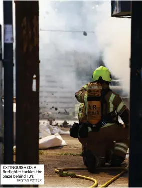  ?? TRISTAN POTTER ?? EXTINGUISH­ED: A firefighte­r tackles the blaze behind TJ’s