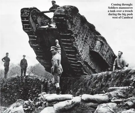  ??  ?? Coming through: Soldiers manoeuvre a tank over a trench during the big push west of Cambrai