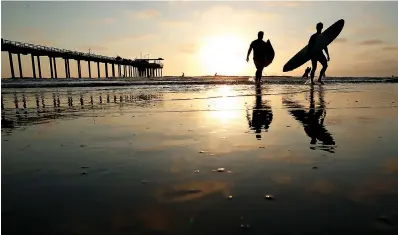  ?? AP Photo/Gregory Bull ?? ■ Surfers leave the water Aug. 2 next to Scripps Pier in San Diego. The Scripps Institutio­n of Oceanograp­hy says it has recorded the highest sea-surface temperatur­e in San Diego in its 102 years of taking measure. The organizati­on says water at the pier reached 78.6 degrees Fahrenheit on Aug. 1, surpassing a previous high set during an unusually warm period in July 1931.