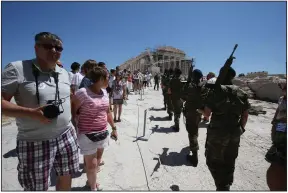  ?? (AP) ?? Tourists look on as members of Greece’s Presidenti­al Guard march past at the Acropolis in this file photo. The pandemic continues to take a toll on the country’s tourist industry as travel uncertaint­ies persist.