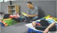  ?? John Locher, The Associated Press ?? Darian Tharp reads to children at the Mccarran 24hour child care center.