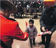  ?? KEVIN KING / POSTMEDIA NEWS FILES ?? Jasjot Mann, 5, takes a flag from a Mountie during a citizenshi­p ceremony in Winnipeg in December 2017.