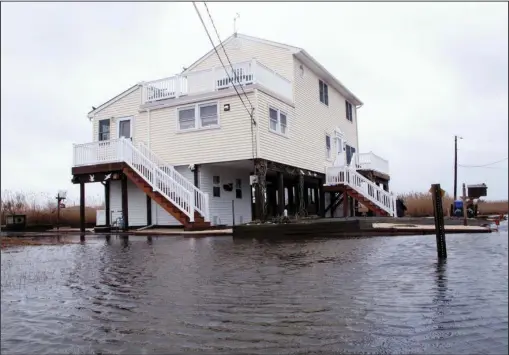  ?? The Associated Press ?? MODERATE STORM: This March 14 photo shows Jim and Maryann O’Neill’s home in a back-bay neighborho­od of Manahawkin N.J., surrounded by water after a moderate storm. Back-bay flooding is a type of recurring nuisance flooding that affects millions of...