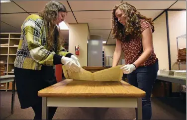  ?? (Arkansas Democrat-Gazette/Staci Vandagriff) ?? Using protective gloves, archival assistant Chelsea Cinotto (left) and Katie Adkins, project manager, carefully turn pages of the Arkansas Farmer newspaper Friday, Nov. 18, 2022, at the Arkansas State Archives headquarte­rs in Little Rock.