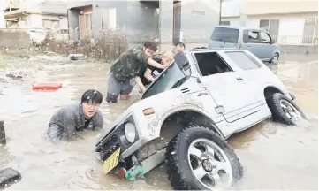  ?? — AFP photo ?? Residents try to upright a vehicle stuck in a flood hit area in Kurashiki.