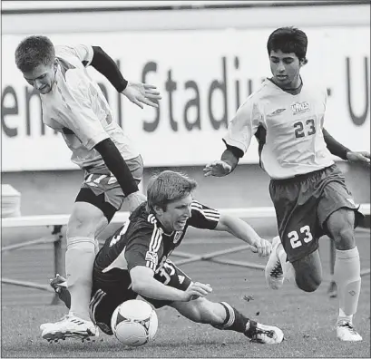  ?? ADRIAN LAM — TIMES COLONIST ?? Greg Klazura of the Whitecaps (centre) goes to ground under pressure from Uvic players during an exhibition soccer game at Centennial Stadium in Victoria on Sunday.