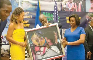  ?? AP-Yonhap ?? U.S. Open champion Naomi Osaka is presented with a gift from Haiti's President Jovenel Moise and first lady Martine Etienne Joseph during a welcoming ceremony at the National Palace in Port-au-Prince, Haiti, Thursday. The Haitian-Japanese tennis star is in the Caribbean for a 5-day visit.