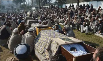  ??  ?? Relatives sit alongside the coffins of victims of a deadly attack in Jalalabad, Afghanista­n, on Monday. At least 14 people were killed when a suicide bomber struck the home of a prominent politician on Sunday, officials said, the second deadly attack...