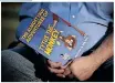  ?? ?? TOBY Price sits at his home with the children’s book he read to a group of secondgrad­ers, which led to his firing from a US elementary school. Inset: Price wrote his own children’s book, a story of “kindness, chaos and autism”. | RORY DOYLE