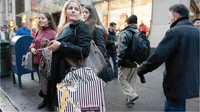  ??  ?? NEW YORK: People carrying shopping bags along Fifth Ave. on Saturday in New York City. Last-minute shoppers hit the stores the day before Christmas. —AFP