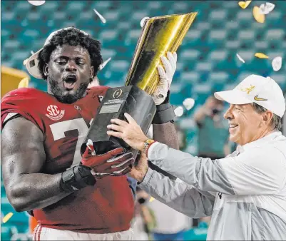  ?? Lynne Sladky The Associated Press ?? Alabama coach Nick Saban and offensive lineman Alex Leatherwoo­d hoist their hardware after Monday’s rout of Ohio State.