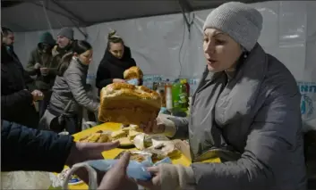  ?? Associated Press ?? A volunteer on Friday gives free meals to people who lost electrical power after a recent Russian rocket attack in the town of Vayshhorod, north of Kyiv, Ukraine.