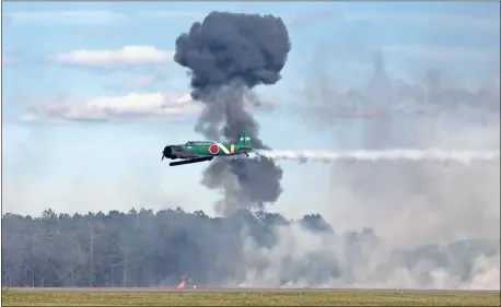  ?? / Doug Walker ?? Smokes rises from one explosion as an aircraft simulating a Japanese Zero at Pearl Harbor strafes the runway at the Wings Over North Georgia.