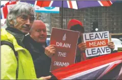  ?? The Associated Press ?? LOST ANOTHER: Pro-Brexit protesters hold out their placards and flags as traffic moves past the Houses of Parliament in London, Monday. The European Commission says the fact that British Prime Minister Boris Johnson did not sign a letter requesting a three-month extension of the Brexit deadline has no impact on whether it is valid and that the European Union is considerin­g the request.