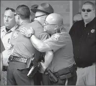  ?? Arkansas Democrat-Gazette/STATON BREIDENTHA­L ?? Law enforcemen­t officers comfort one another Friday afternoon outside the funeral home in Dardanelle where the body of Lt. Kevin Mainhart was taken.