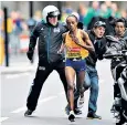  ??  ?? Security guards tackle a spectator who almost ran into Jemima Sumgong