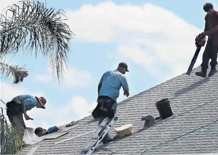  ?? STEPHEN M DOWELL/ORLANDO SENTINEL ?? Roofers complete a new shingle installati­on on a home in Winter Garden on March 18.