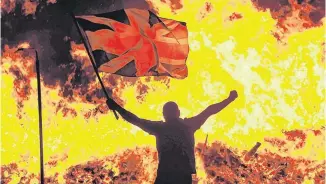  ??  ?? Fiery topic: A loyalist celebrates at a Belfast 11th-night bonfire