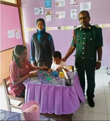  ??  ?? Eager to learn: Famisah studying with his teacher at SJK( T) Ladang Ban Heng in Pagoh as Ropiah and Selvam look on.