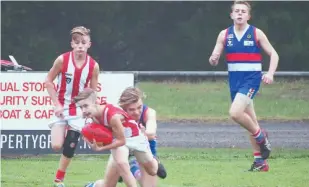  ??  ?? Trafalgar’s Blair Young is wrapped up in a tackle during the under 16 match against Newborough