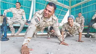  ??  ?? Iraqi soldiers Corporal Sergeant Ali Radhi and Private Ali Hassan do push- ups during weapons training.