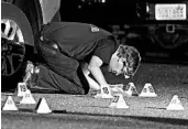  ?? TED S. WARREN/AP ?? A Washington state crime lab worker looks at markers Friday at the scene where Michael Reinoehl was killed.