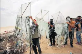  ?? Said Khatib AFP/Getty Images ?? PALESTINIA­NS prepare kites to be f lown across the border with burning rags attached, part of a new tactic of setting wheat fields on the Israeli side on fire.