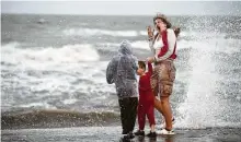  ?? Brett Coomer / Staff photograph­er ?? Reighny Knight turns as she, Elijah Melendez, left, and Peyton Knight get splashed by one of Beta’s choppy waves.