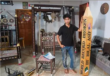  ??  ?? Pakistani artist Bilal posing for a photograph with his pencil art work at his studio in Karachi. — AFP