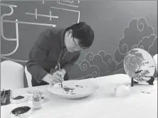  ??  ?? Right: Li Wenyue, a Jingdezhen porcelain maker from Jiangxi province, creates a painting on a plate at the expo.