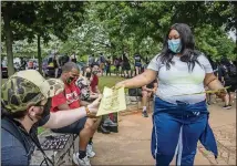  ??  ?? Protest organizer Mary-Pat Hector hands out literature during a peaceful protest march from Cleopas Park to Atlanta City Hall Sunday.