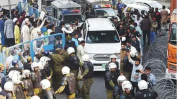  ?? AFP ?? Policemen escort a vehicle carrying arrested Pakistani opposition leader Shahbaz Sharif, as he arrives for a hearing at the accountabi­lity court in Lahore yesterday.