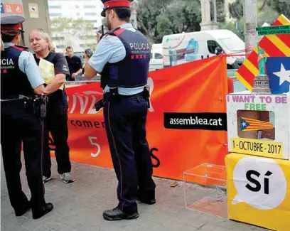  ??  ?? TENSIÓN. Miembros de los Mossos interrogan a un hombre que protesta por la negativa de Madrid a que se celebre la consulta.