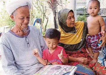  ??  ?? MAT Nawi bersama isteri, Sabariah Mamat melihat akhbar melaporkan mengenai Mohd Sazarim dan Nur Anisa yang maut dalam kemalangan di Jalan Salor Baru sambil diperhatik­an Muhamad Amin Syahiran dan Muhamad Anas Akil di rumah mereka di Kampung Sat Hulu,...