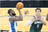  ?? JOHN RAOUX/AP ?? Magic forward James Ennis III shoots over Bucks center Brook Lopez during the first half of Sunday’s game in Orlando. The Magic lost 124-87.