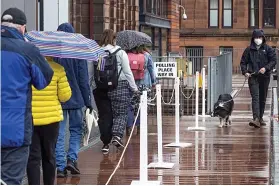  ??  ?? Determined: Waiting in rain at Notre Dame primary in Glasgow