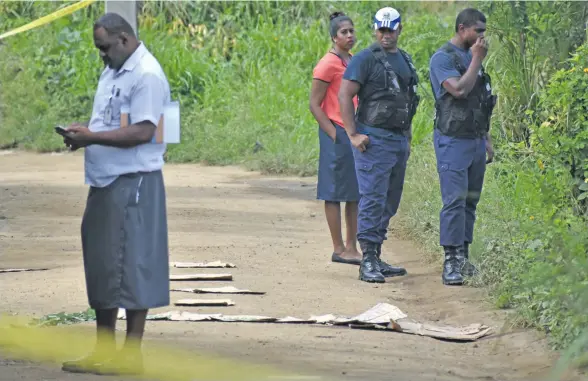  ?? Photo: Arieta Vakasukawa­qa ?? A team of Police officers at the crime scene where Asbin Nair was found dead just a few metres away from his home in Jubaraki Settlement in Olosara, Sigatoka, on June 7, 2018. Covered in carton cuttings are the blood trails which led to where the body...