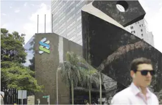  ??  ?? SINGAPORE: People walk past the Standard Chartered building yesterday in Singapore. Singapore regulators announced yesterday fines amounting to over $5.3 million for two banks that were found to have breached money laundering rules in dealings with an...