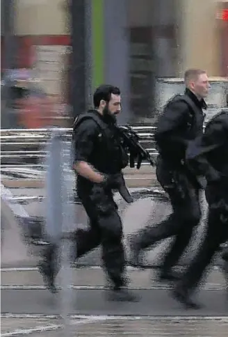  ??  ?? FAST REACTION: In this grab taken from video, police run in the area of the Olympia Einkaufsze­ntrum mall after the shooting, in Munich, which killed and wounded numerous people last night