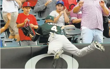  ?? MARKJ. TERRILL/ASSOCIATED PRESS ?? A’s left fielder Coco Crisp climbs the wall to rob the Angels’Ji-Man Choi of a home run in the fifth inning Thursday in Anaheim.