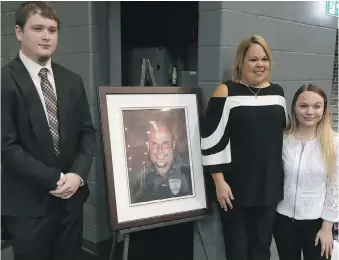  ??  ?? Above: Sr. Const. John Atkinson’s widow, Shelley and children Mitchell and Nicole stand with a photo of the officer. Below: Attendees at the ceremony stand at attention. At bottom: The sign near St. Clair College along the Herb Gray Parkway that bears...