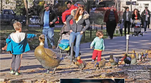  ??  ?? A boy points at a sculpture of a mother duck and her ducklings, based on the classic children’s story ‘Make Way for Ducklings’ at the Boston Public Garden in Boston.