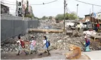  ?? Agence France-presse ?? Schoolgirl­s walk past a sewage drain canal full of garbage in the Taimur Nagar slum area in New Delhi.