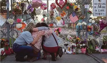  ?? AFP PIC ?? People hugging at the makeshift memorial in front of Marjory Stoneman Douglas High School in Parkland, Florida, on Sunday.