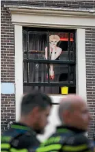  ?? AP ?? Two police officers keep watch as sex workers welcome clients again in Amsterdam’s De Wallen red-light district.