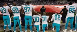  ?? GRANT HALVERSON / GETTY IMAGES ?? Miami’s Kenny Stills (10), Michael Thomas (31) and Julius Thomas kneel during the national anthem at the start of Monday’s game at Carolina.