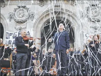  ?? Kamil Zihnioglu The Associated Press ?? Michel Dietlin, center, stands with striking orchestra musicians after a performanc­e Saturday outside the Palais Garnier opera house in Paris. As some strikers return to work, more radical protesters are trying to keep the movement going.